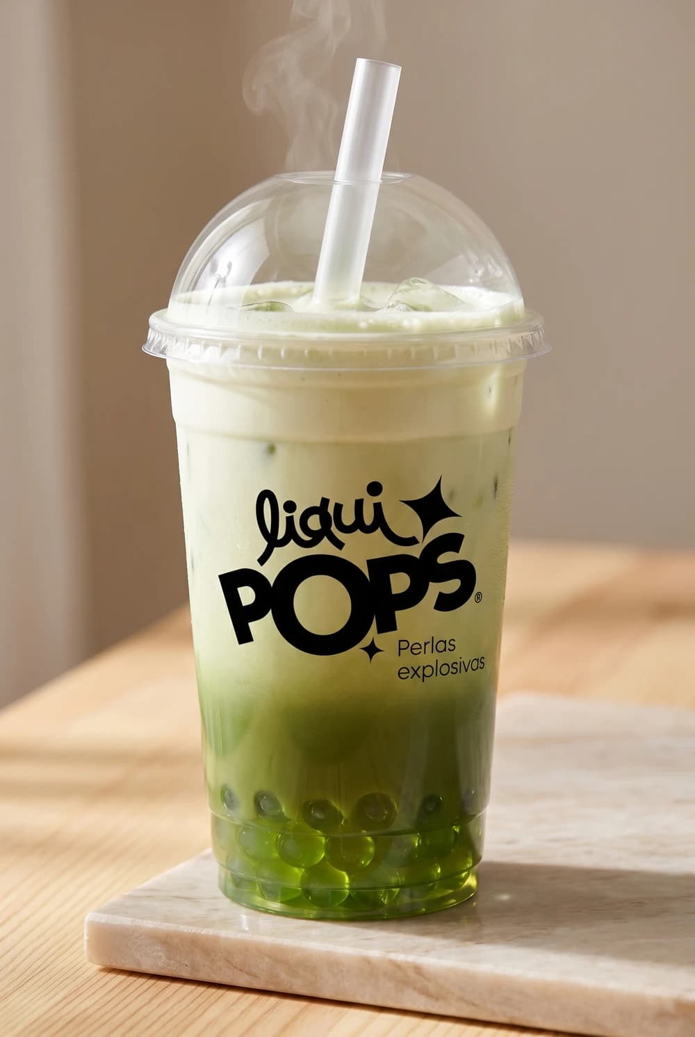 Matcha latte caliente con perlas explosivas verdes LiquiPops — vaso humeante con tapa domo