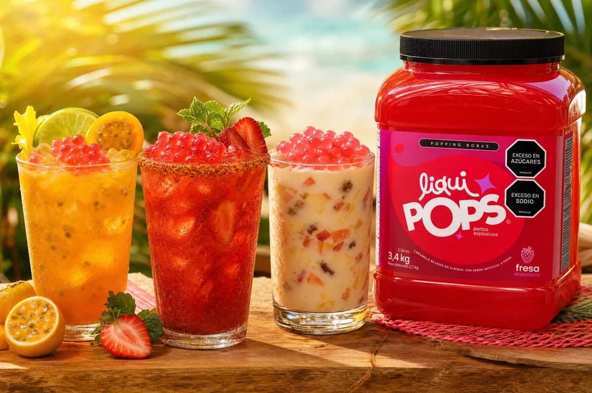 Bebidas tropicales con perlas explosivas de fresa LiquiPops y balde de producto en escena de playa — ambiente veraniego