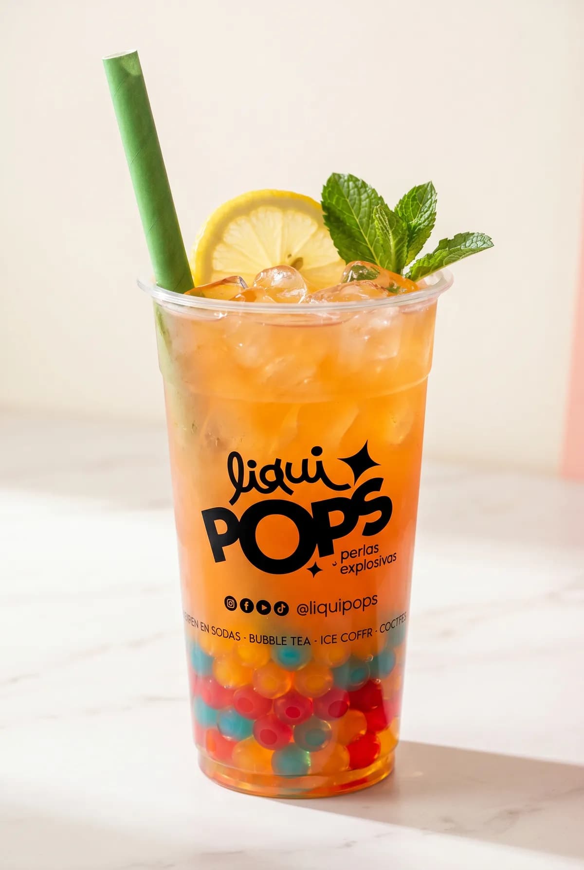 Bubble tea de durazno con perlas explosivas de colores LiquiPops — vaso con menta y limón sobre mármol