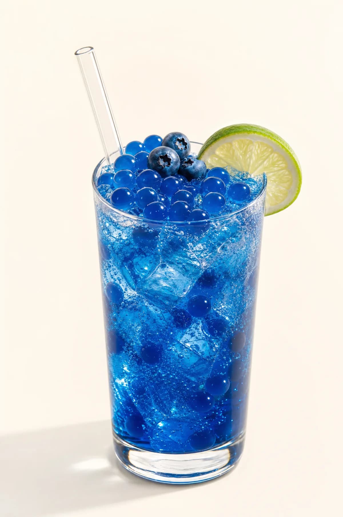 Soda azul de arándano con perlas explosivas LiquiPops — vaso con hielo, arándanos y rodaja de limón