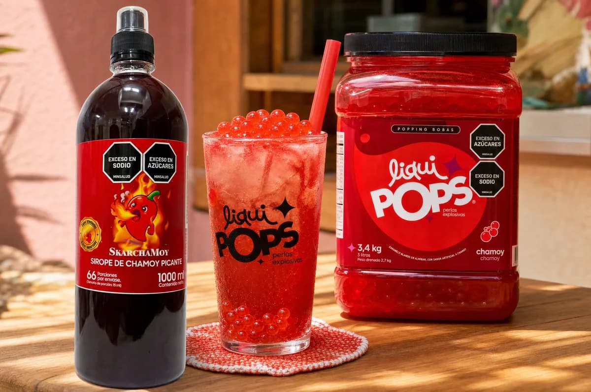 Soda roja de chamoy con perlas explosivas LiquiPops, botella de sirope Skarchamoy picante y tina de chamoy de 3,4 kg sobre mesa de madera al aire libre