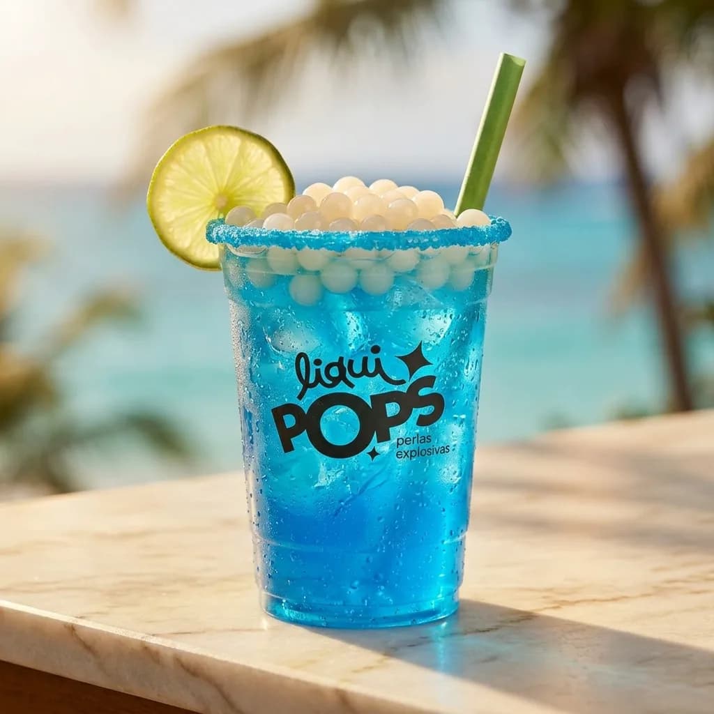 Soda loca azul con perlas explosivas de coco LiquiPops — vaso escarchado con limón frente al mar