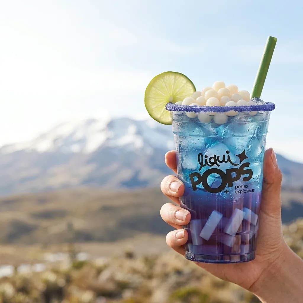Soda loca azul y morada estilo galaxia con perlas explosivas blancas de litchi LiquiPops y escarchado lila, frente a un nevado