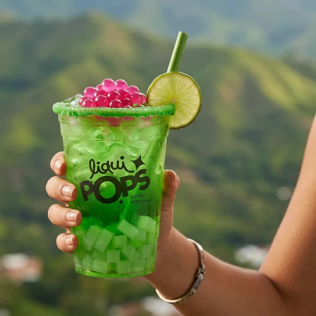 Soda loca verde de manzana con perlas explosivas rosadas de fresa LiquiPops y escarchado verde, con montañas al fondo