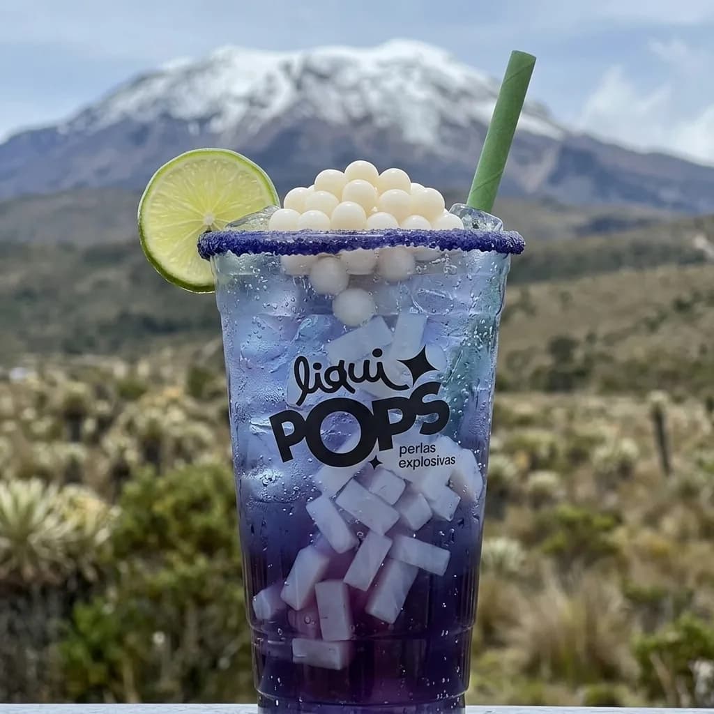 Soda loca morada con perlas explosivas de litchi y cubos de coco LiquiPops, frente a una montaña nevada