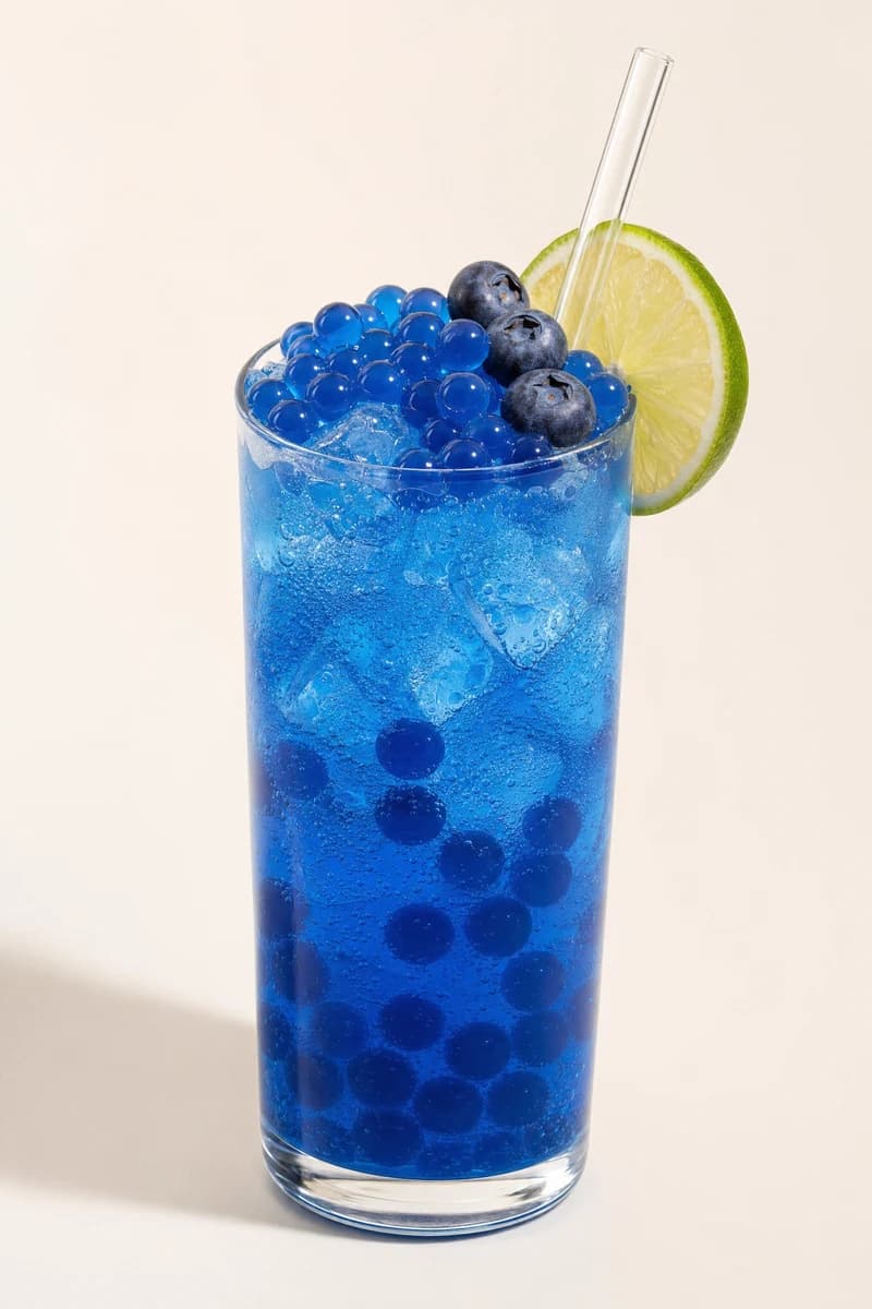 Soda azul de blueberry con perlas explosivas LiquiPops, arándanos frescos y rodaja de limón — bebida con gas en vaso alto
