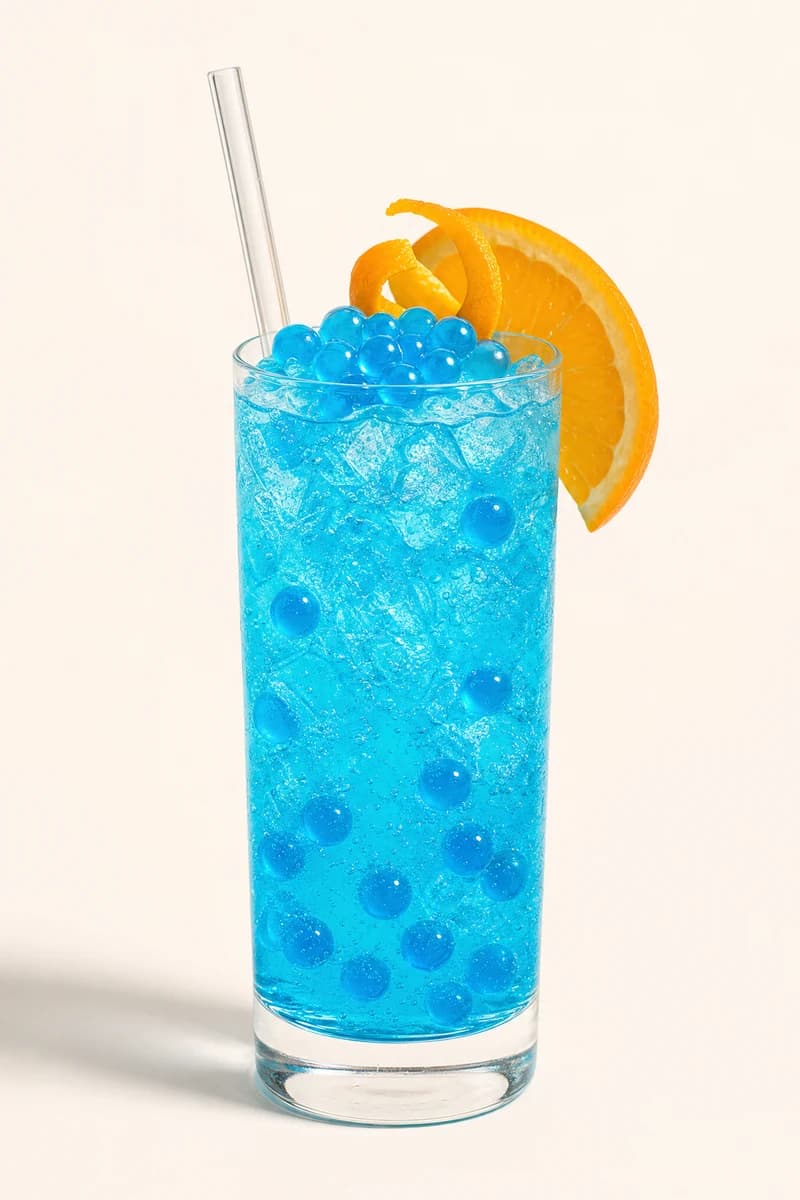 Soda azul de curazao con perlas explosivas LiquiPops y cáscara de naranja en vaso alto con hielo y gas