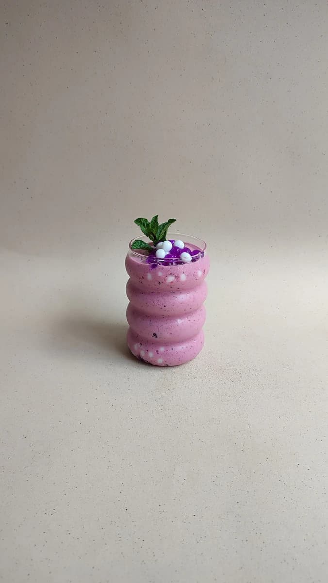 Smoothie de frutos rojos con perlas explosivas LiquiPops y hierbabuena sobre fondo beige