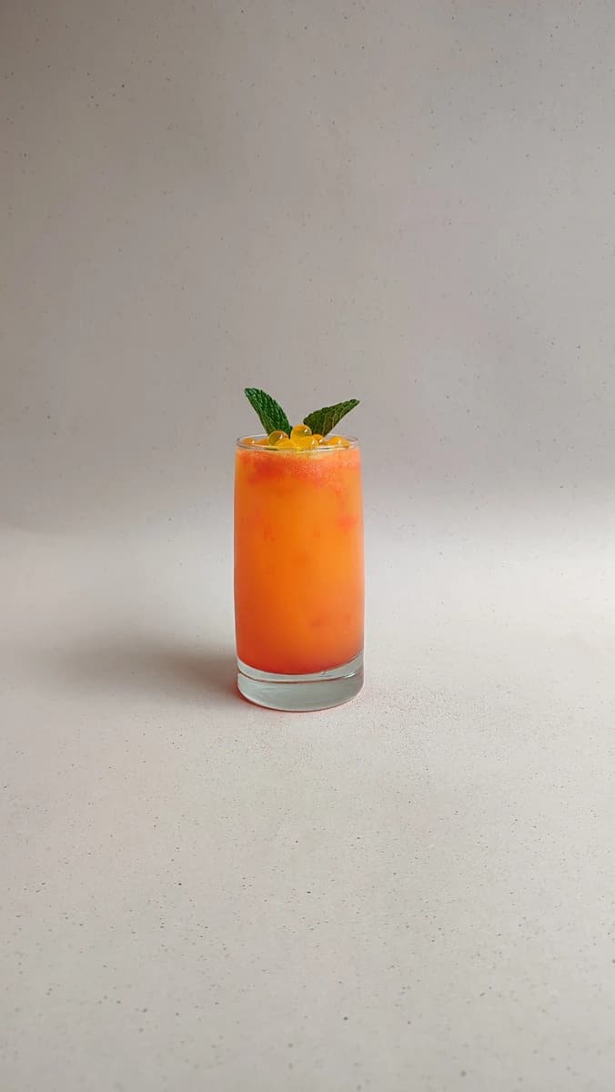 Soda de maracuya color naranja con perlas explosivas LiquiPops y menta en vaso largo — receta de bebida frutal