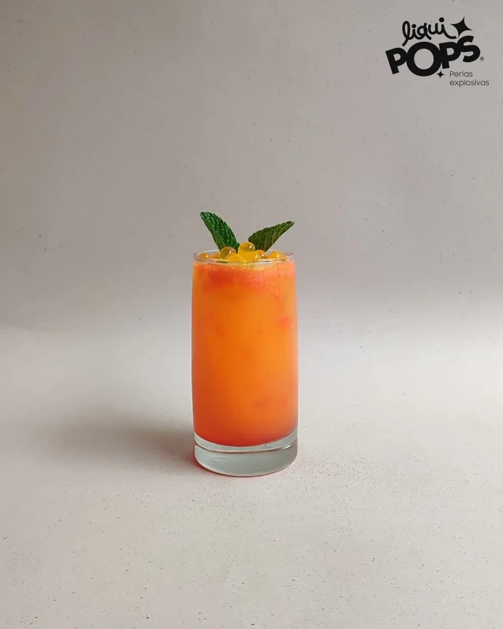 Soda de maracuya naranja con perlas explosivas LiquiPops y hojas de menta en vaso alto — bebida refrescante de fruta