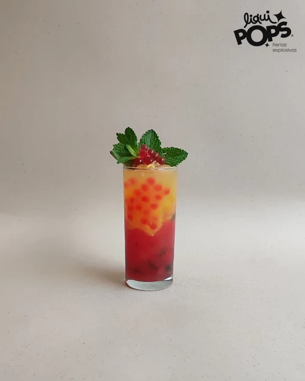 Soda en capas de sandia y naranja con perlas explosivas rojas LiquiPops y grosellas en vaso alto — receta de bebida frutal