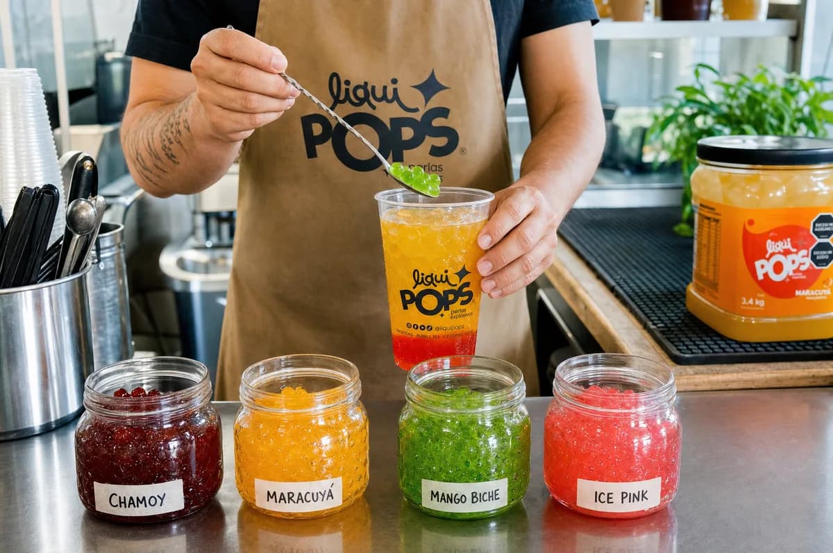 Barista LiquiPops añadiendo perlas explosivas a un vaso de bebida con frascos de sabores chamoy, maracuyá, mango biche e ice pink