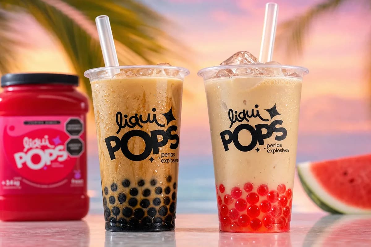 Dos vasos de bubble tea cremoso con perlas clasicas oscuras y perlas explosivas rojas LiquiPops junto al tarro, ambiente de playa
