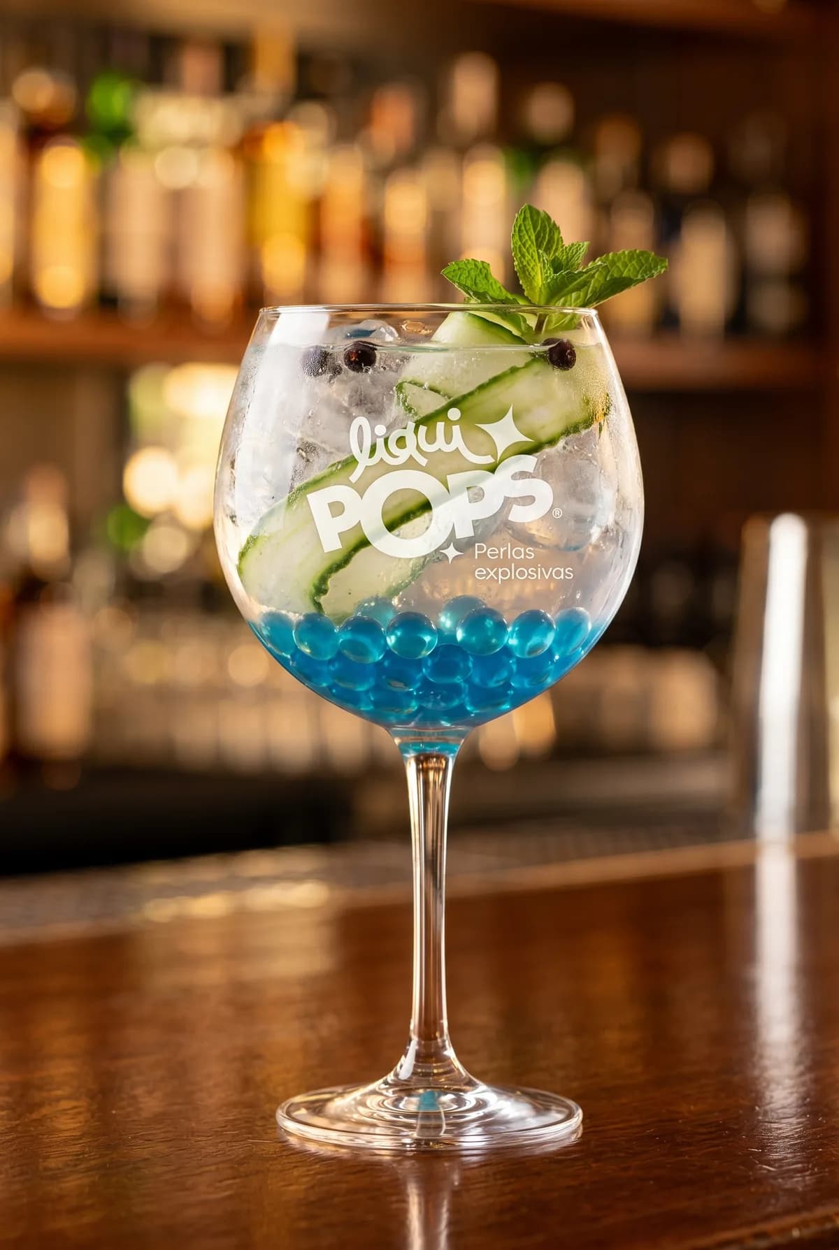 Gin tonic con pepino, menta y perlas explosivas azules LiquiPops en copa balón sobre la barra