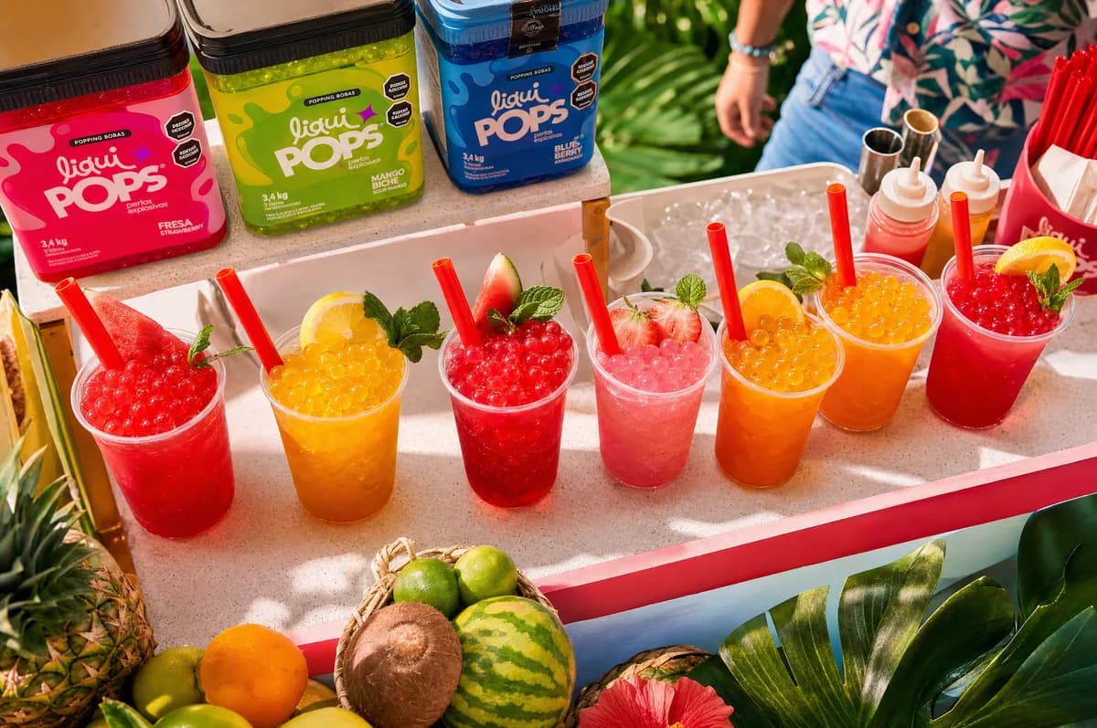 Fila de granizados frutales de colores con perlas explosivas LiquiPops sobre un carrito con frutas frescas