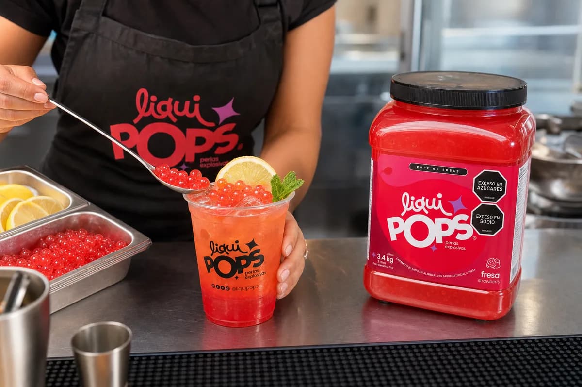 Limonada de fresa con perlas explosivas rojas LiquiPops servida en barra junto al bote de fresa y bandeja de perlas