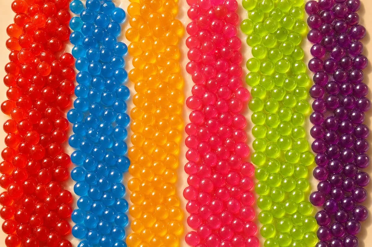 Filas de perlas explosivas LiquiPops de colores surtidos vistas de cerca — rojo, azul, naranja, rosa y verde