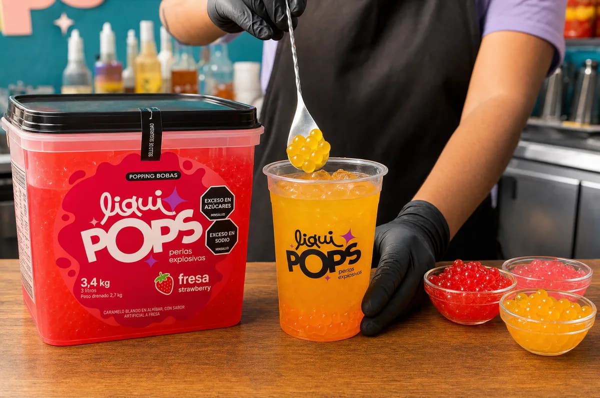 Balde de perlas explosivas LiquiPops sabor fresa junto a vaso de bebida y boles de perlas — barra de preparación