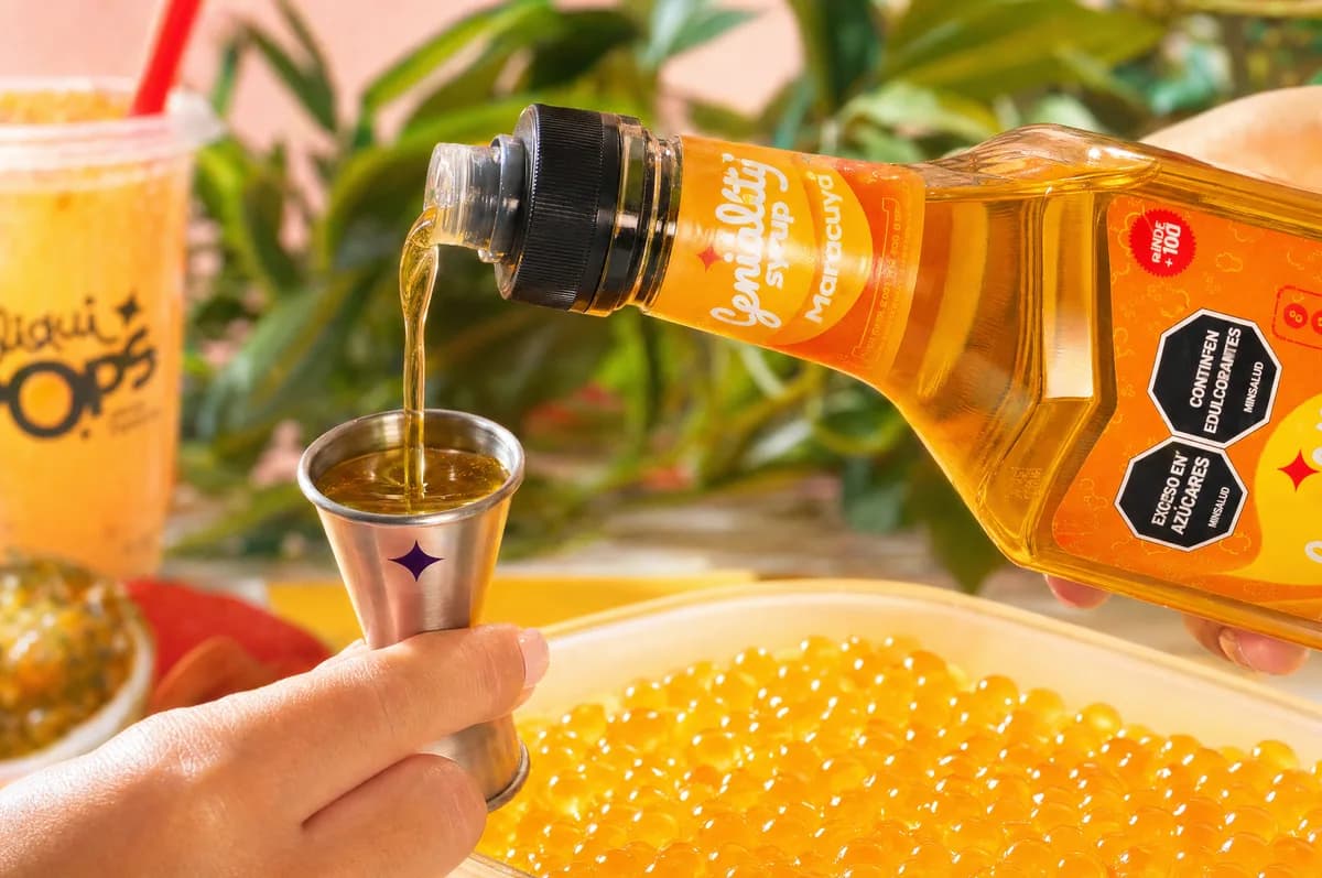 Sirope Geniality sabor maracuyá by LiquiPOPS sirviéndose sobre una bandeja de perlas explosivas amarillas