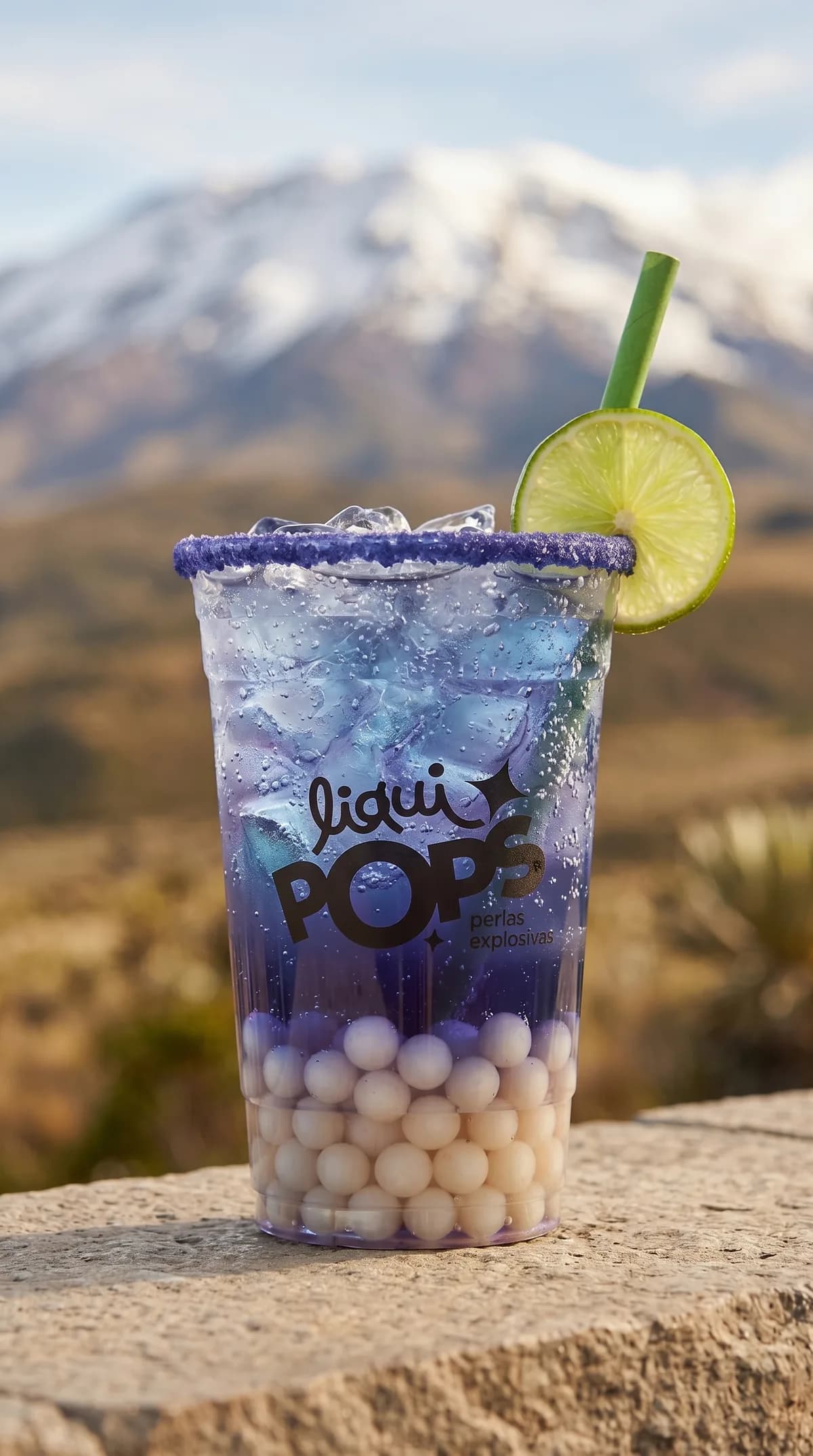 Soda loca azul violeta con perlas explosivas LiquiPops y rodaja de limon, frente a montañas nevadas