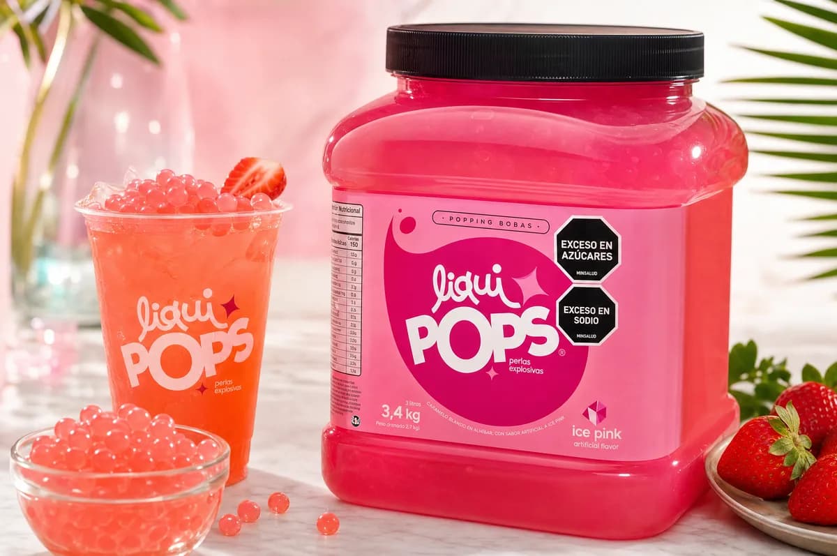 Tarro de perlas explosivas LiquiPops sabor ice pink de 3,4 kg con soda rosada, perlas explosivas LiquiPops en tazon y fresas frescas — color rosado vibrante