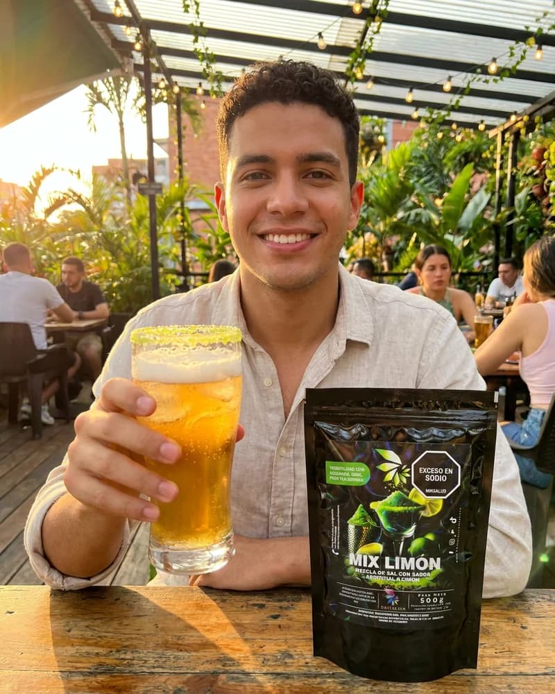 Hombre en terraza al atardecer con vaso de bebida escarchada en limon y sal Skarcha con perlas explosivas LiquiPops junto al empaque by LiquiPOPS