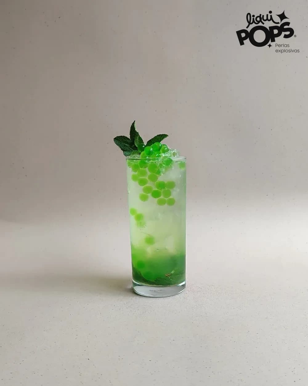 Soda de manzana verde con perlas explosivas verdes LiquiPops y hierbabuena en vaso alto