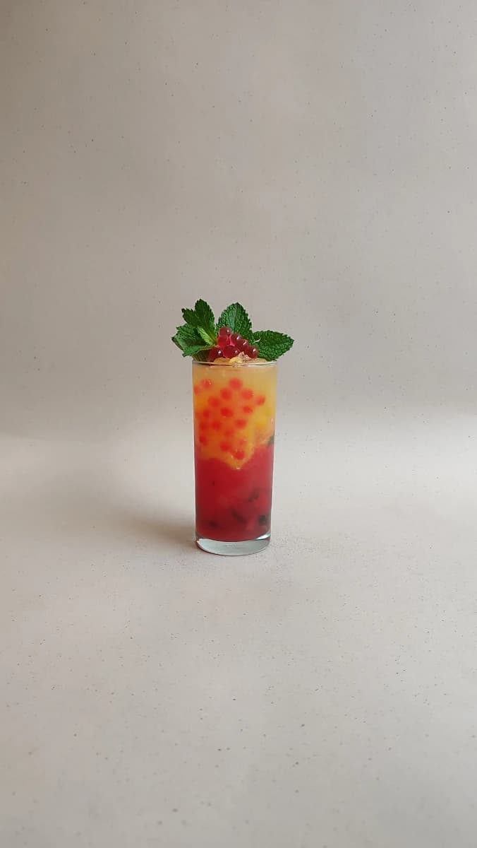 Soda de sandia y naranja con perlas explosivas rojas LiquiPops, menta y grosellas — bebida refrescante en capas