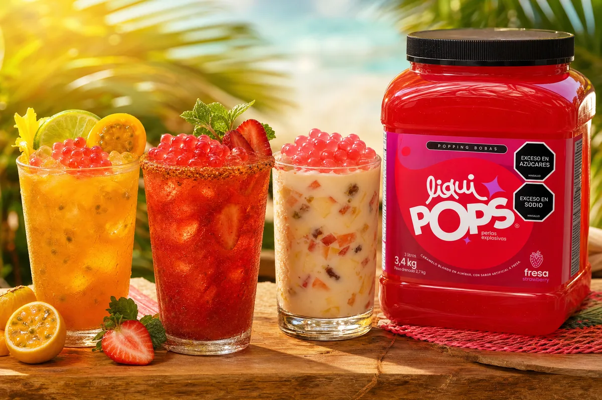 Bebidas tropicales con perlas explosivas de fresa LiquiPops y balde de producto en escena de playa — ambiente veraniego