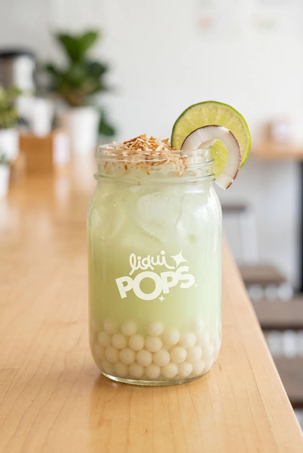 Bubble tea de coco en frasco con perlas blancas LiquiPops, coco rallado tostado y rodaja de limón — sobre mesa de madera