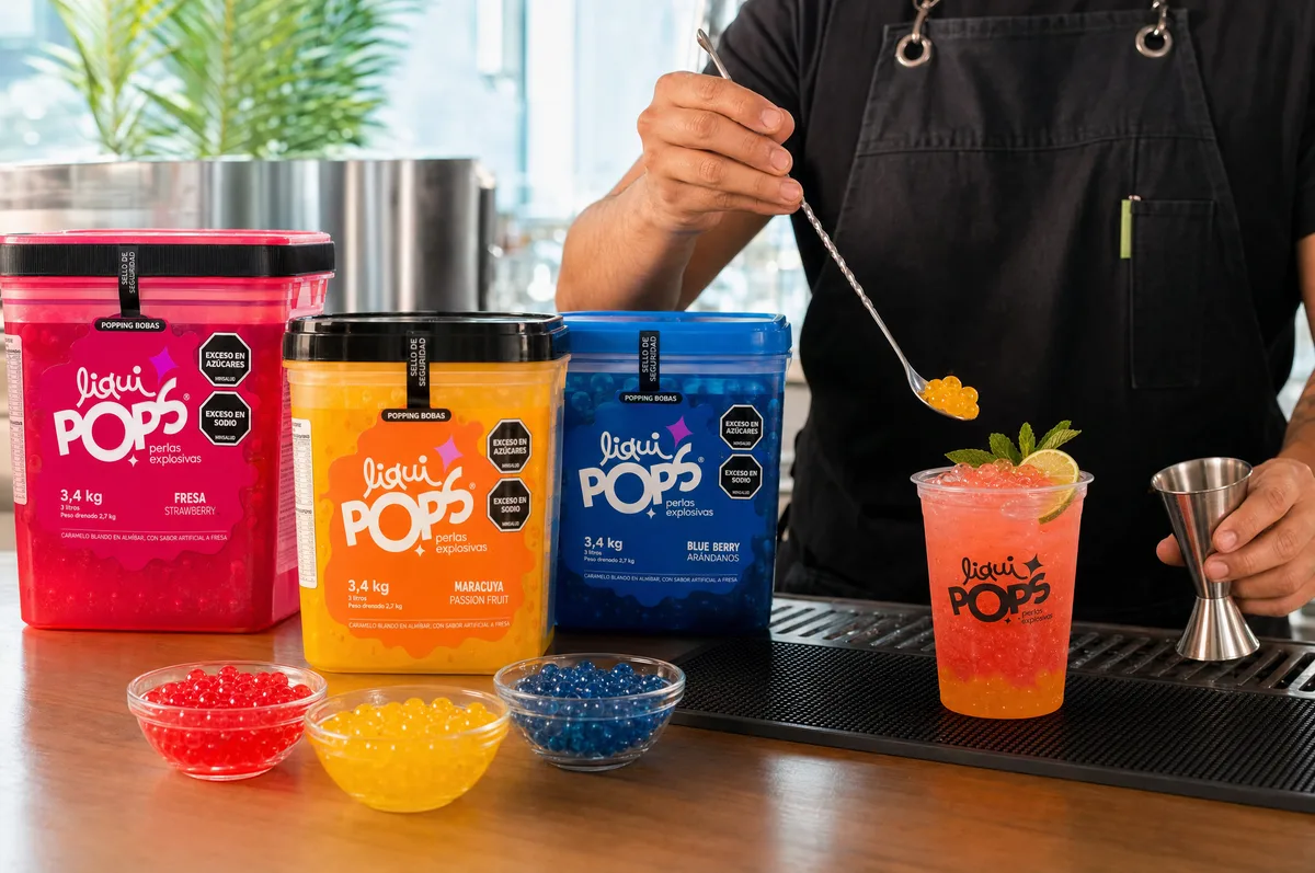 Cóctel con capas de perlas explosivas LiquiPops sabor maracuyá y fresa junto a tarros de fresa, maracuyá y blueberry en barra