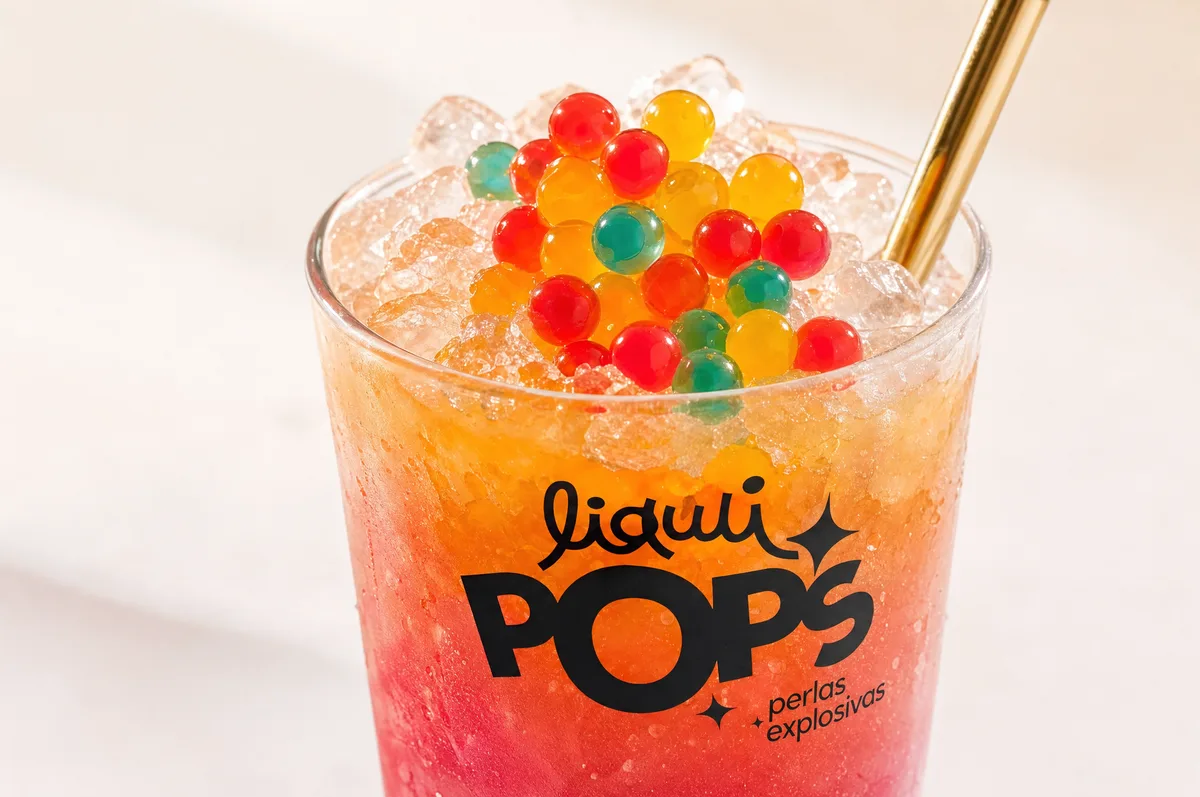 Granizado de frutos rojos y naranja con perlas explosivas LiquiPops encima y pitillo dorado en vaso de marca