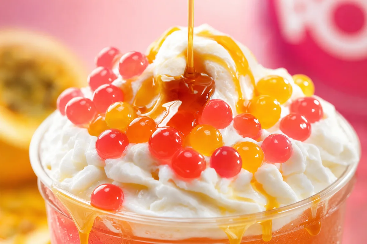 Granizado de maracuyá coronado con crema batida, sirope y perlas explosivas rojas y amarillas LiquiPops — primer plano