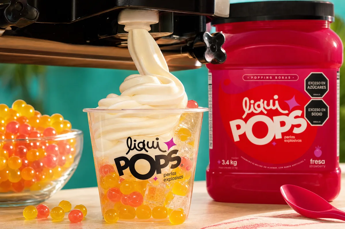 Helado suave servido sobre perlas explosivas naranjas con el tarro de fresa LiquiPops al lado