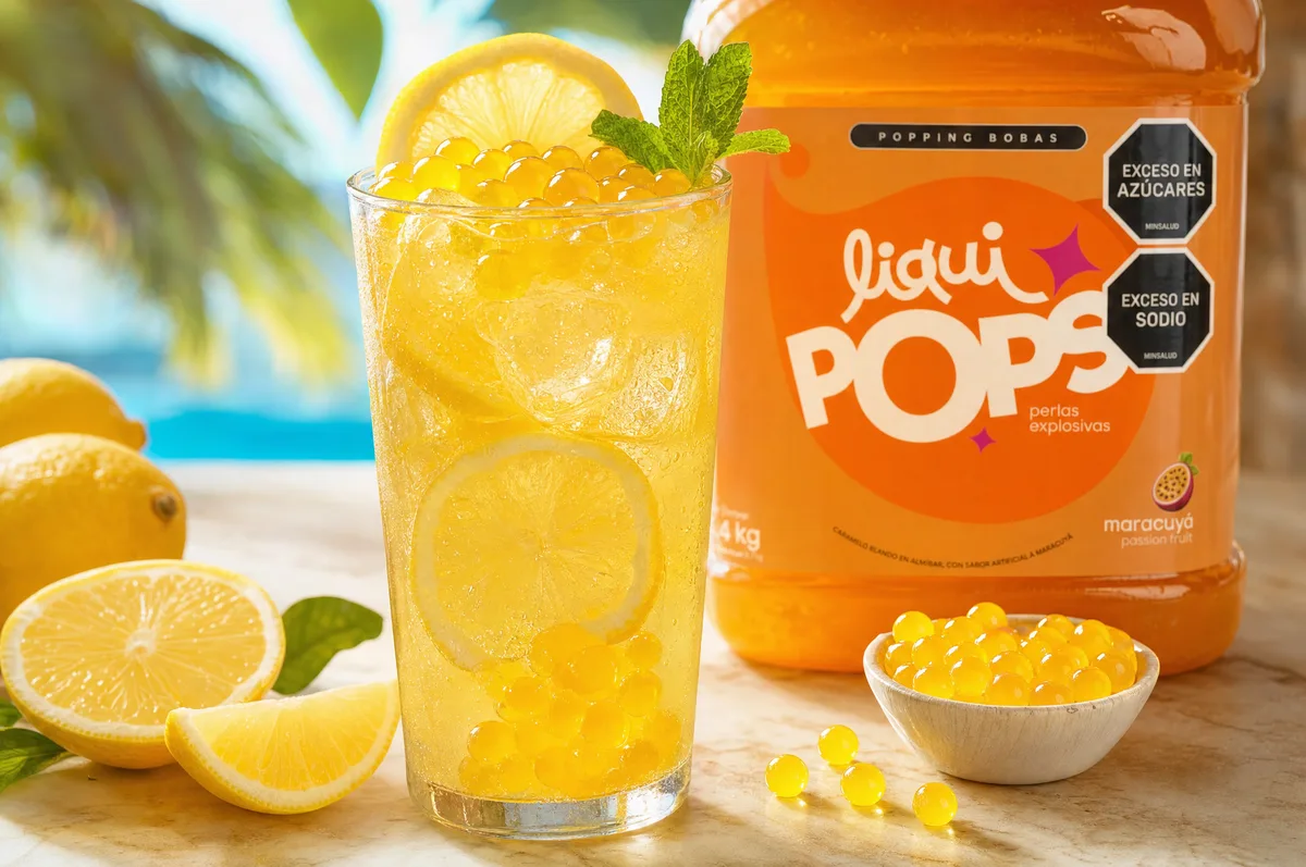 Limonada amarilla de maracuyá con perlas explosivas doradas LiquiPops junto a garrafa de perlas sabor maracuyá — escena junto a piscina