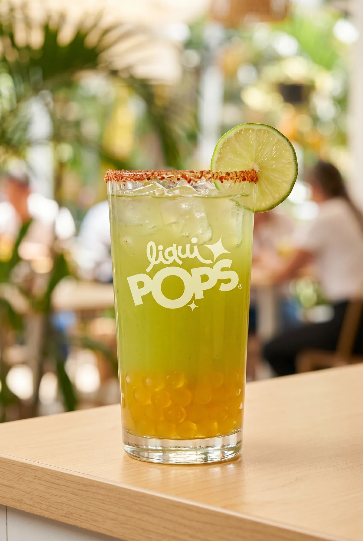 Limonada verde tropical con perlas explosivas amarillas LiquiPops y borde con chile — vaso con rodaja de limón en terraza