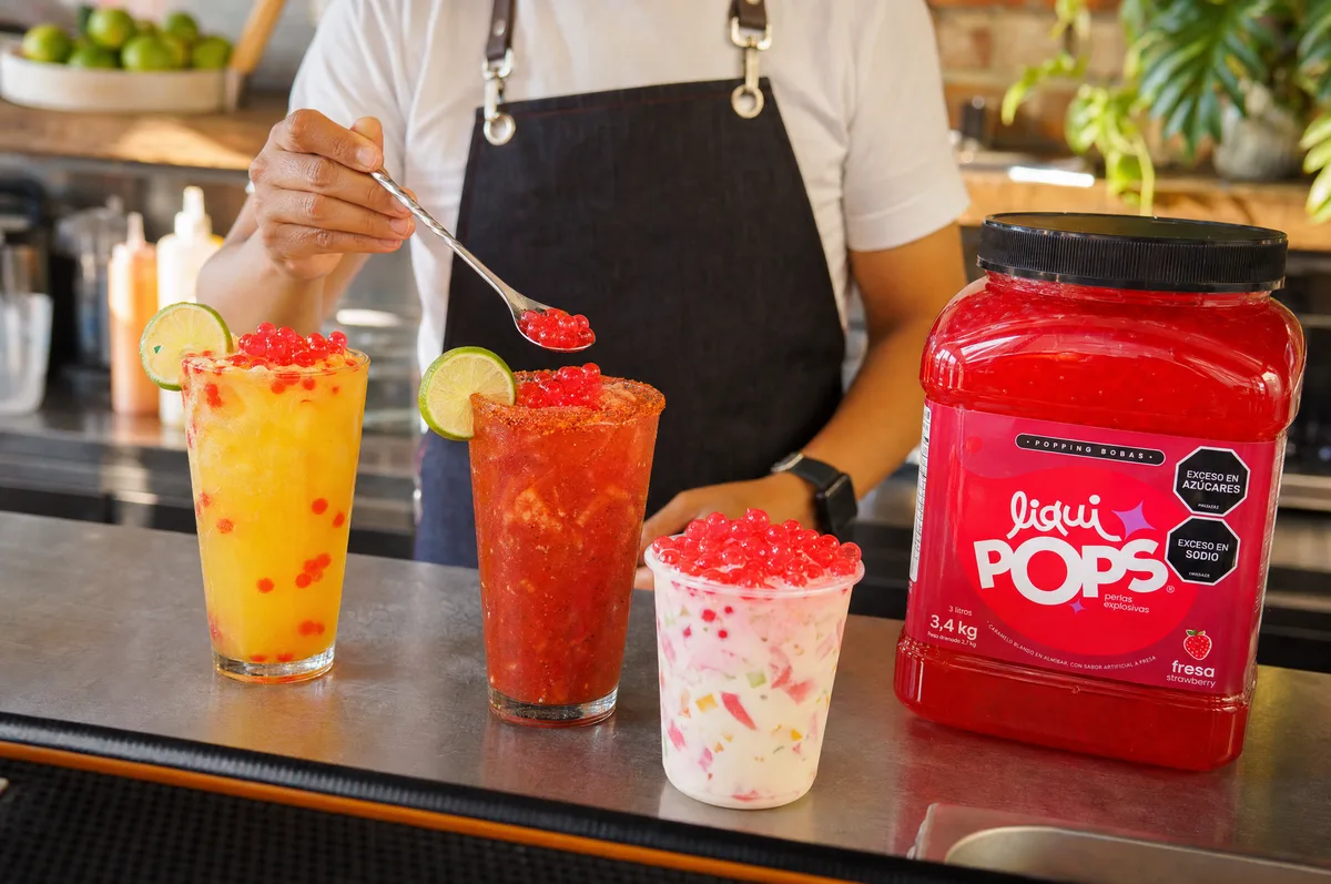 Michelada, soda de mango y cholado con perlas explosivas de fresa LiquiPops junto al balde de producto — barra de bebidas
