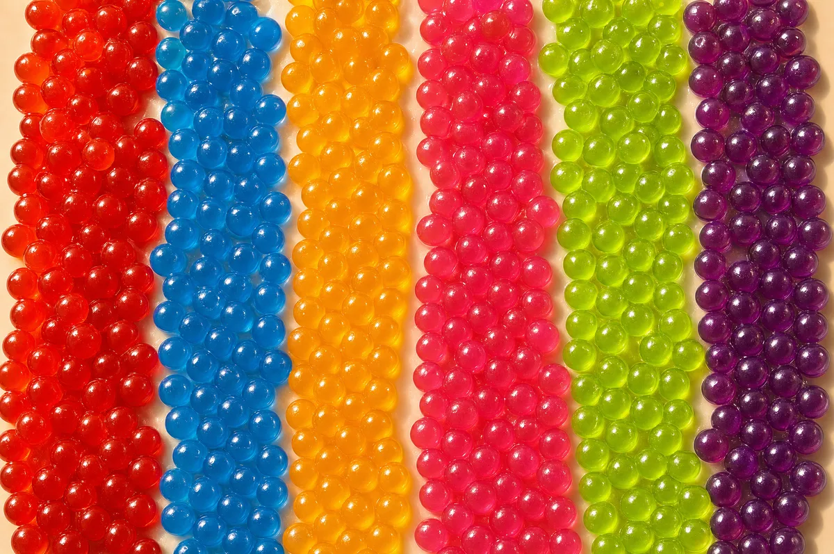 Filas de perlas explosivas LiquiPops de colores surtidos vistas de cerca — rojo, azul, naranja, rosa y verde