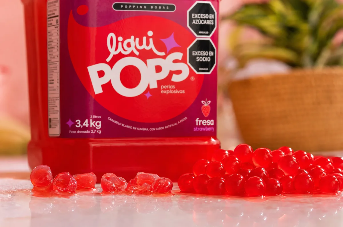 Tarro de perlas explosivas LiquiPops sabor fresa con perlas rojas servidas al lado mostrando su textura brillante