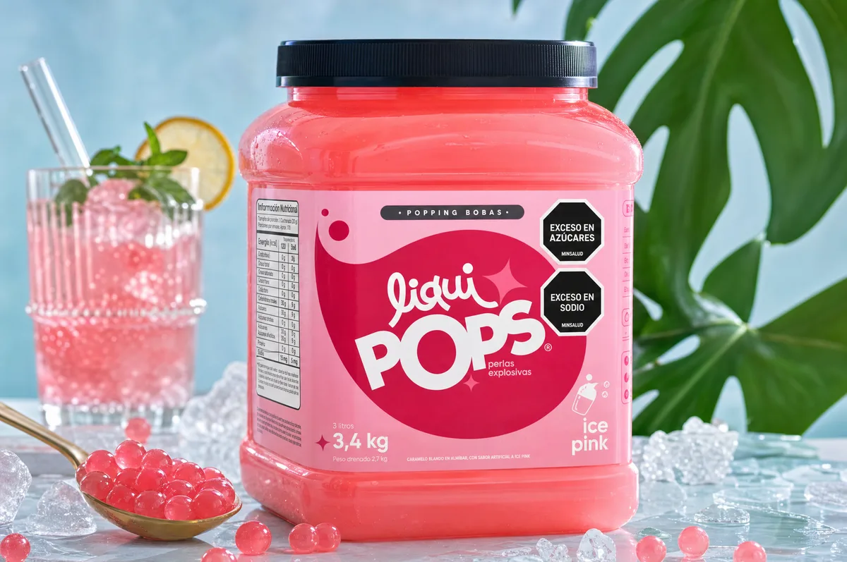 Tarro de perlas explosivas LiquiPops sabor ice pink junto a una soda rosada con limon y hielo