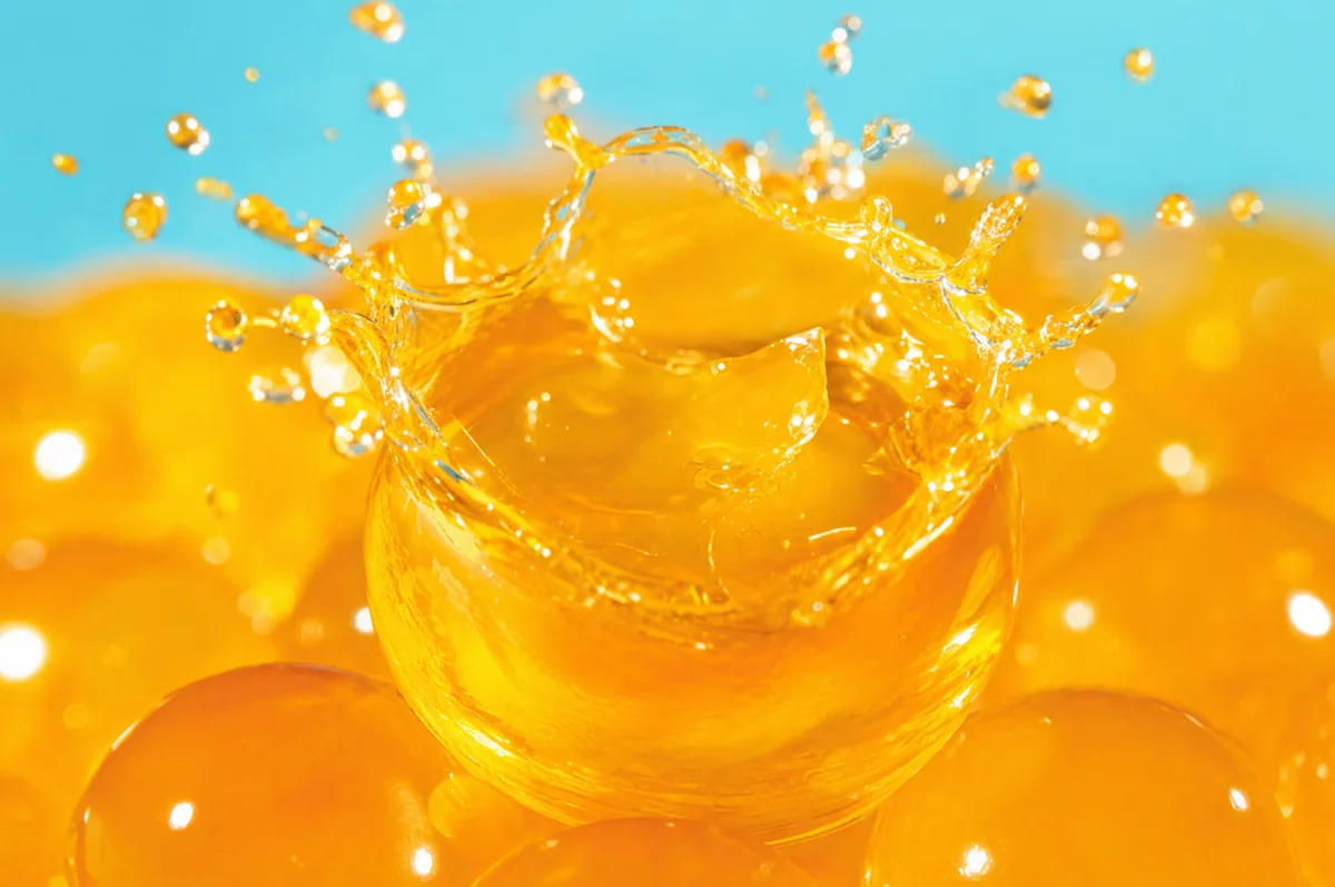 Perlas explosivas naranja sabor mango LiquiPops con salpicadura de jugo sobre fondo celeste — imagen de impacto