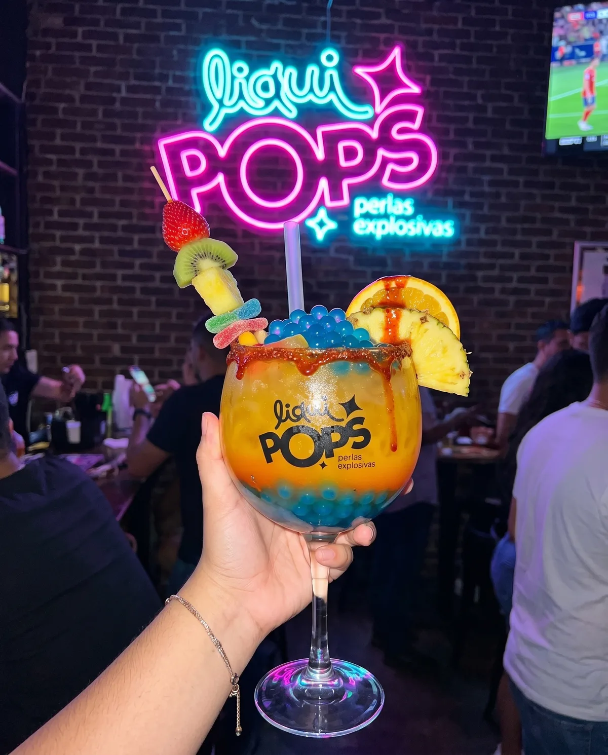 Chica sosteniendo una soda loca rosada con perlas explosivas azules LiquiPops en un bar bajo el letrero neón — pasador de frutas y escarcha