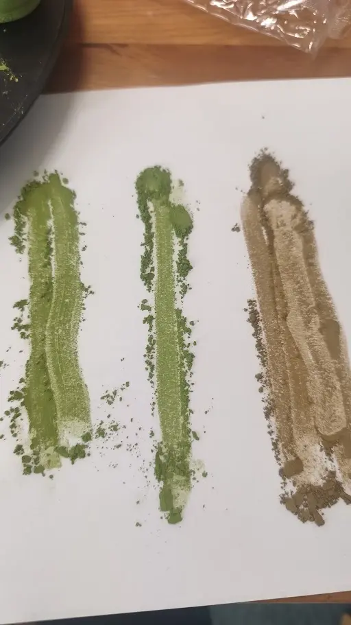 Tres muestras de matcha en polvo sobre papel blanco: dos verdes y una beige