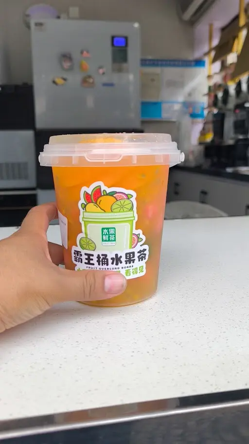 Té de frutas en vaso grande con trozos de fruta en una tienda de Yiwu