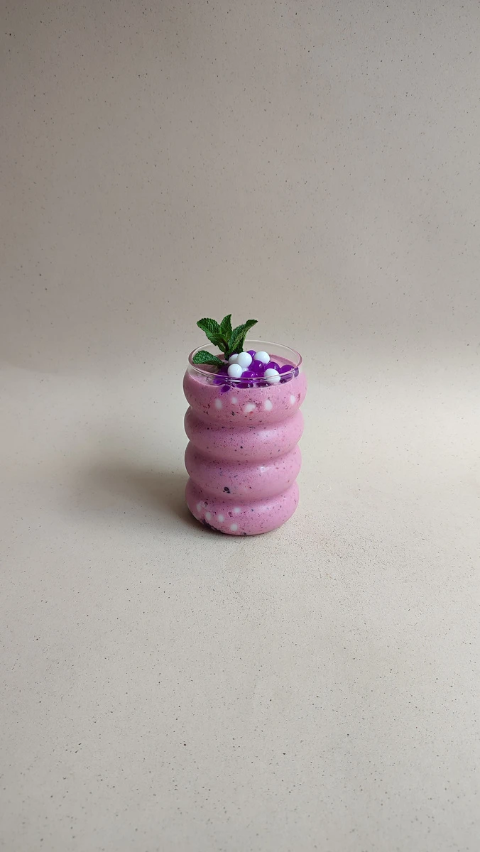 Smoothie de frutos rojos con perlas explosivas LiquiPops y hierbabuena sobre fondo beige