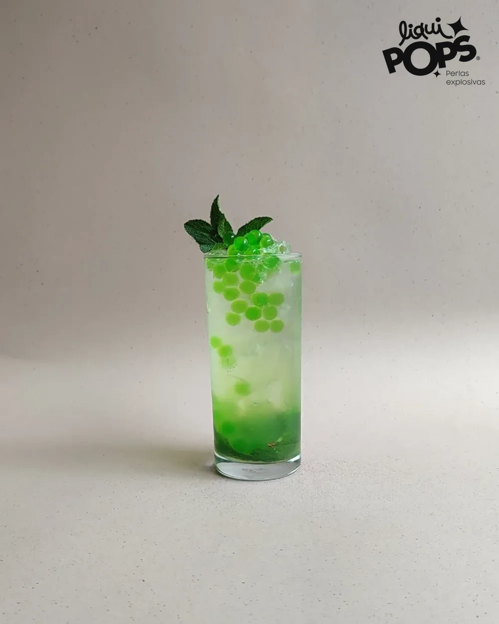 Soda de manzana verde con perlas explosivas verdes LiquiPops y hierbabuena en vaso alto