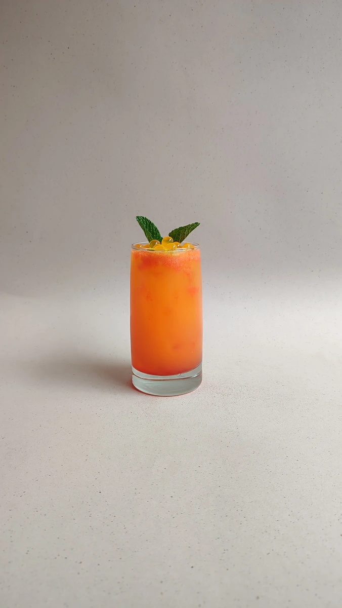 Soda de maracuya color naranja con perlas explosivas LiquiPops y menta en vaso largo — receta de bebida frutal