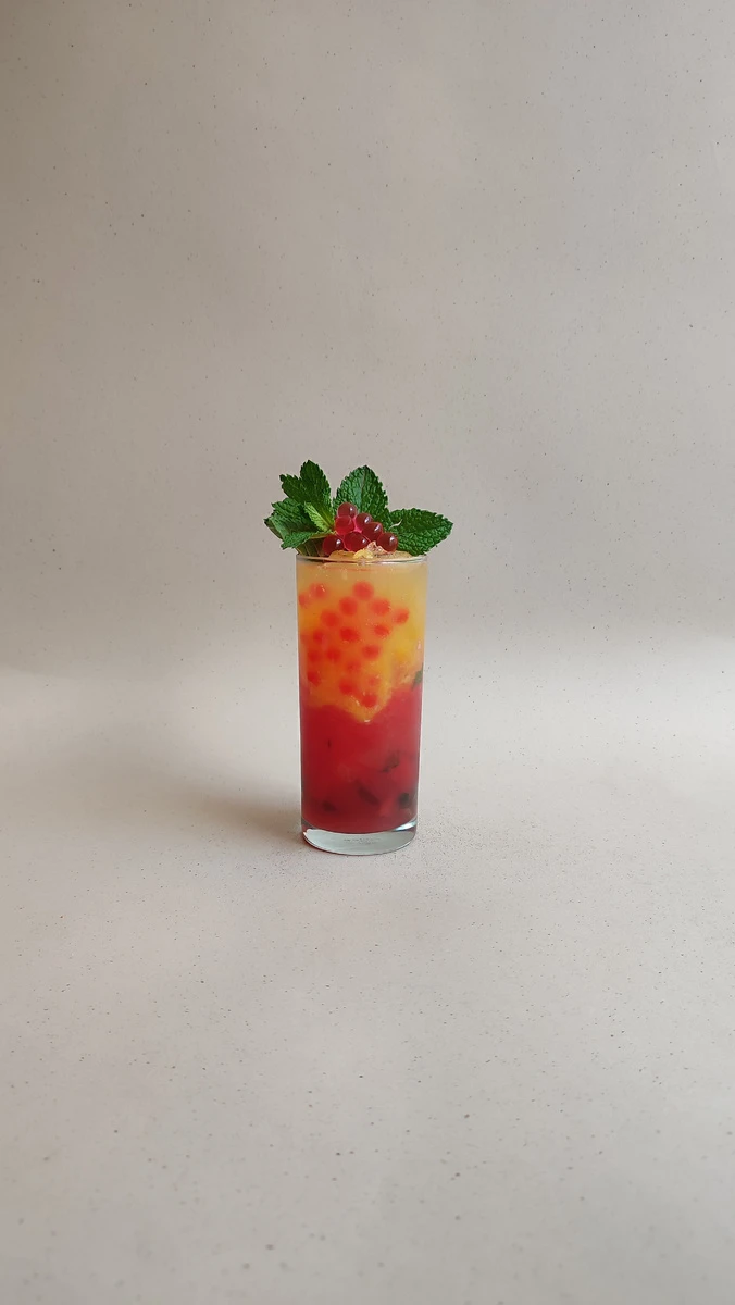 Soda de sandia y naranja con perlas explosivas rojas LiquiPops, menta y grosellas — bebida refrescante en capas