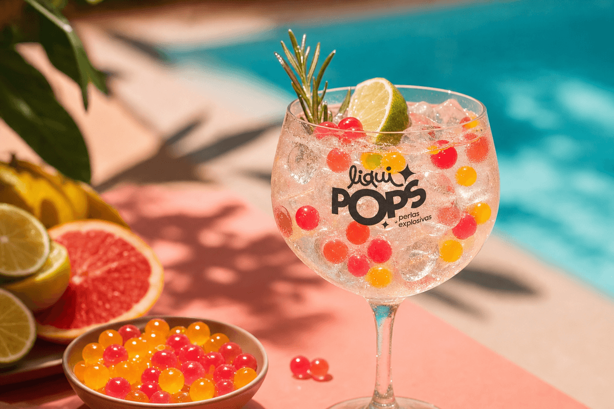 Side-view of a gin tonic in a balloon glass with pink popping boba pearls floating — cócteles con perlas explosivas LiquiPops Colombia