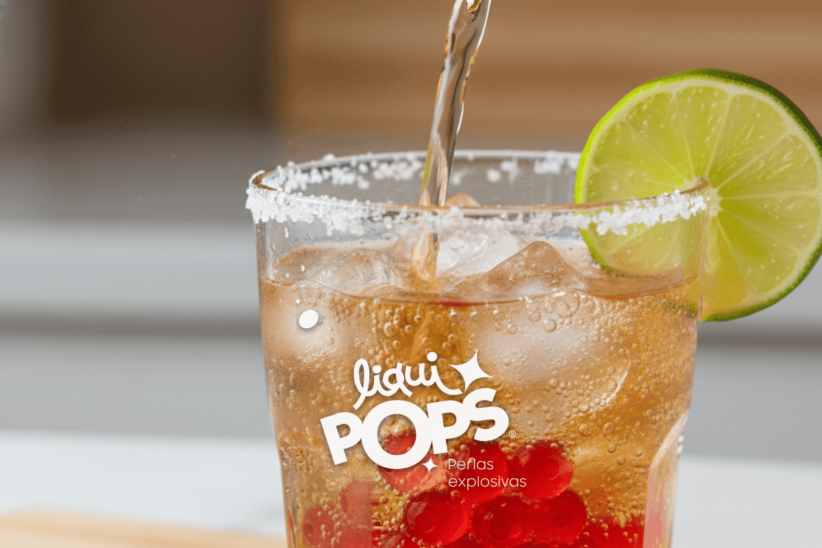Close-up of soda being poured into a salt-rimmed clear glass with ice, bubbles rising, lime wedge ready on the side.